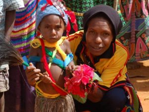 A Papua New Guinea coffee farmer and her child greet specialty coffee importers with flowers upon their arrival to their village